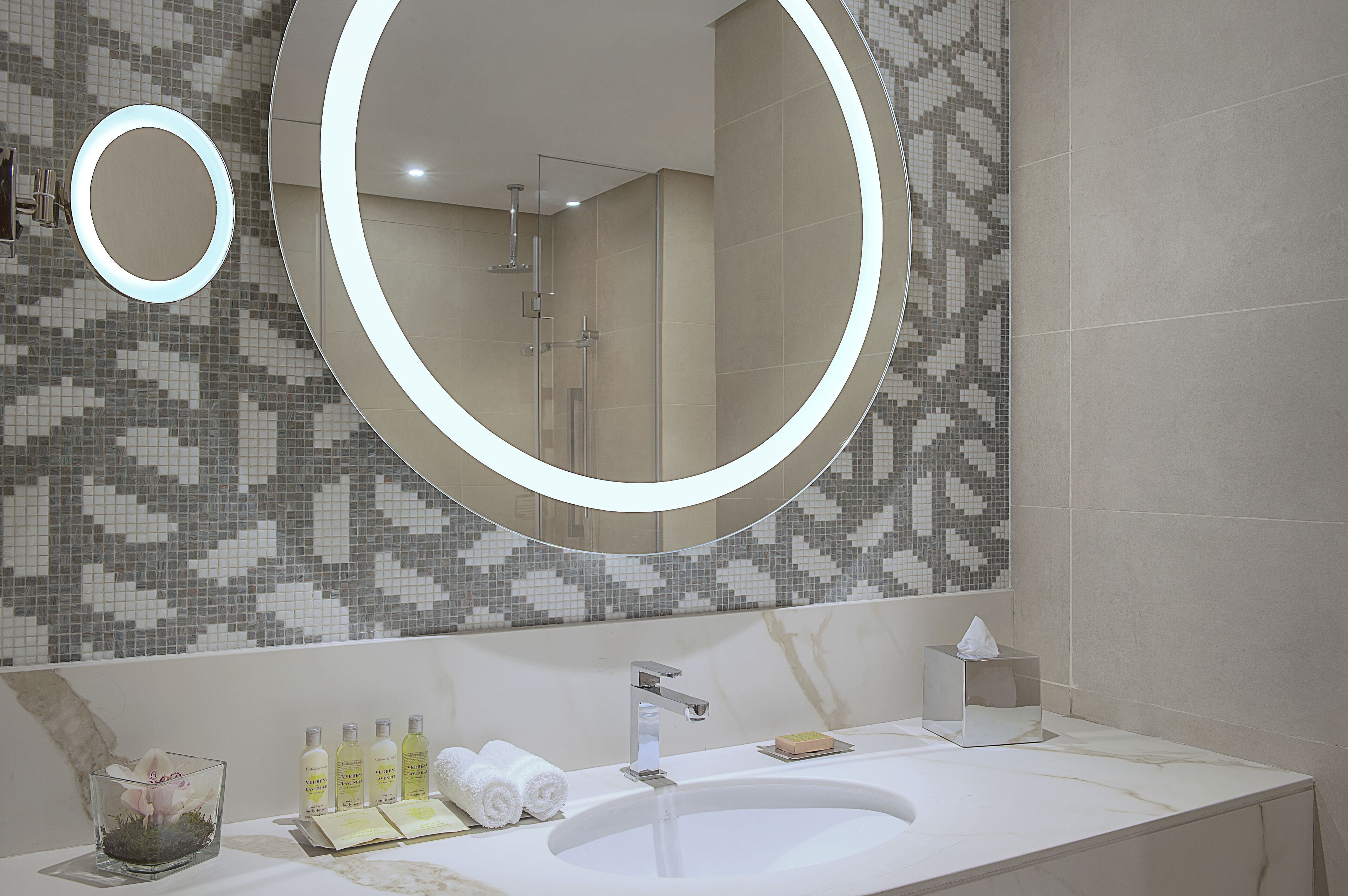 Une salle de bain moderne avec un grand miroir, un lavabo et une douche.