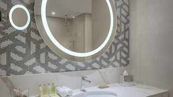 Une salle de bain moderne avec un grand miroir, un lavabo et une douche.