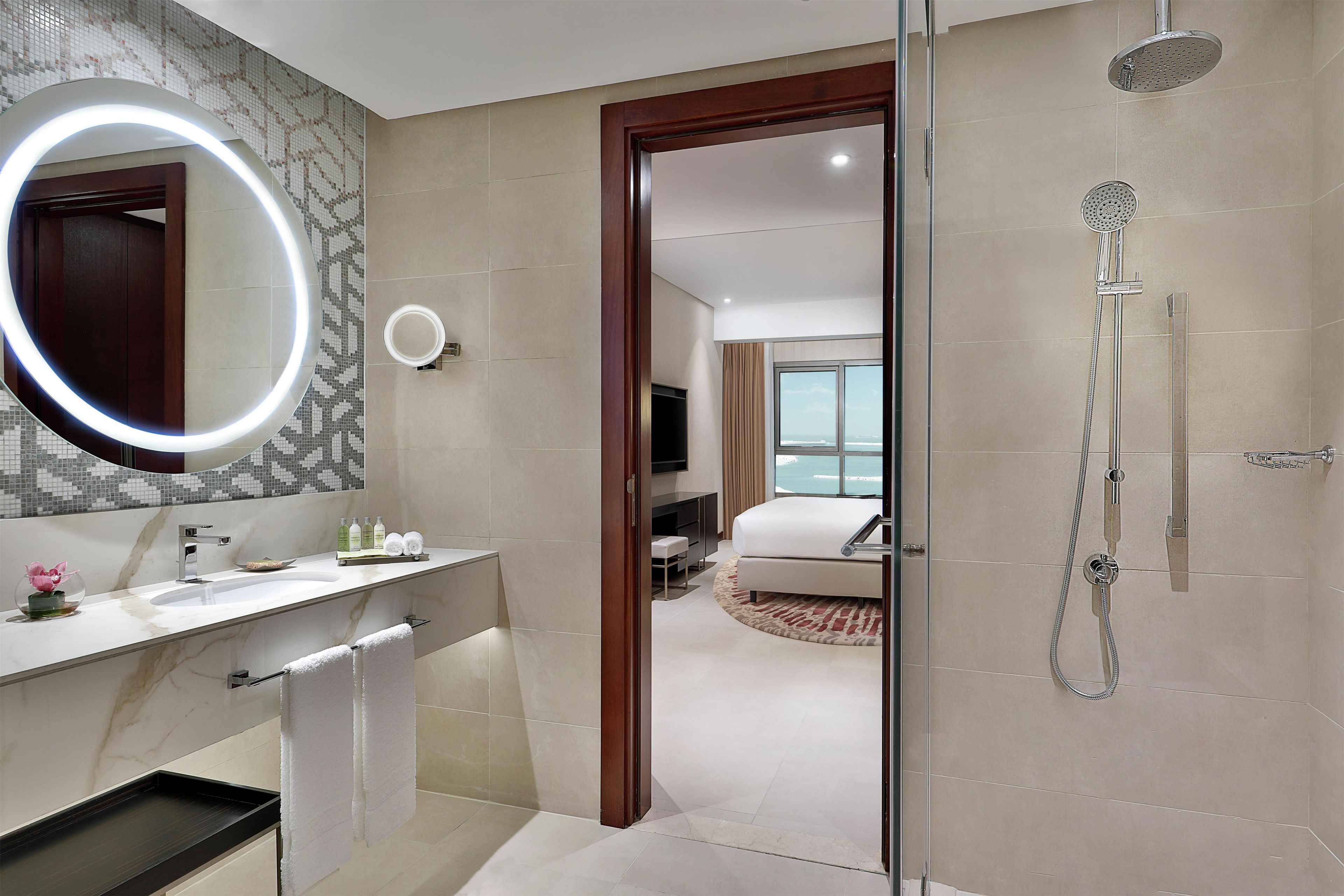 Un baño moderno con ducha envuelta en vidrio, tocador con espejo y un inodoro.