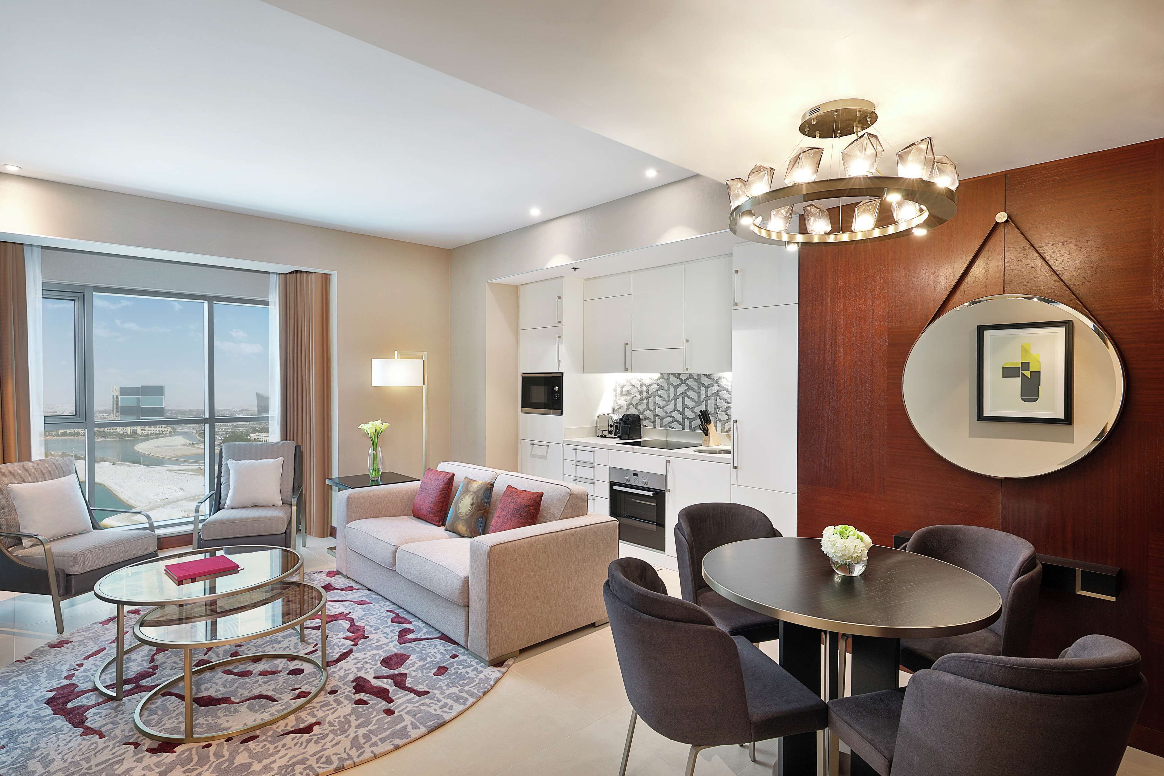 Une chambre d’hôtel moderne dotée d’un espace salon, d’un coin repas et d’une kitchenette.