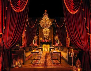 A luxurious room with a grand chandelier, red drapes, and a fireplace. - Hilton Doha The Pearl (Doha)