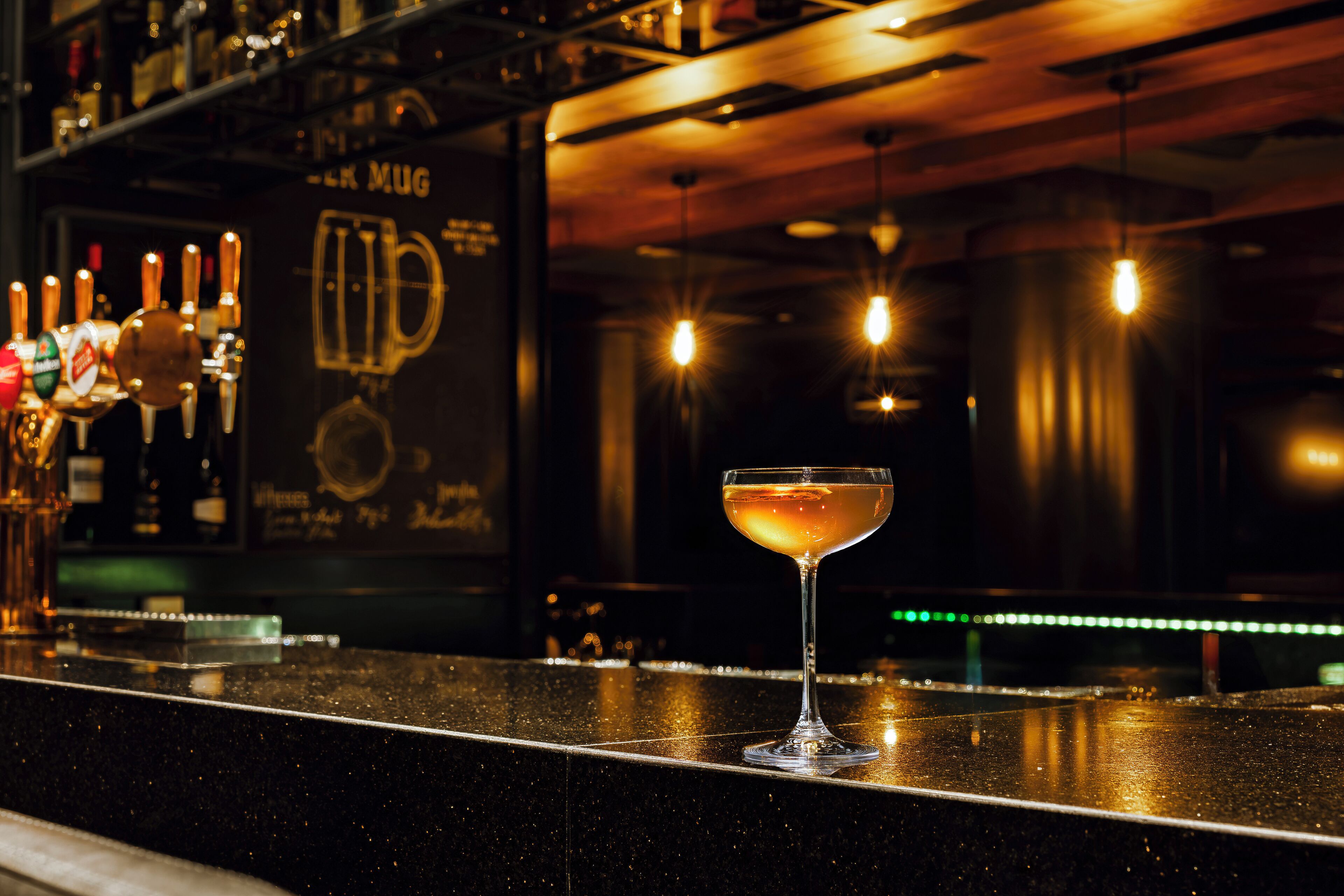 Un bancone bar con un bicchiere di martini e rubinetti per la birra.