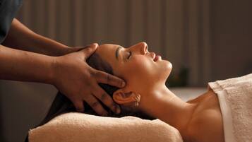 A person receiving a massage in a room with a plain wall and a curtain.