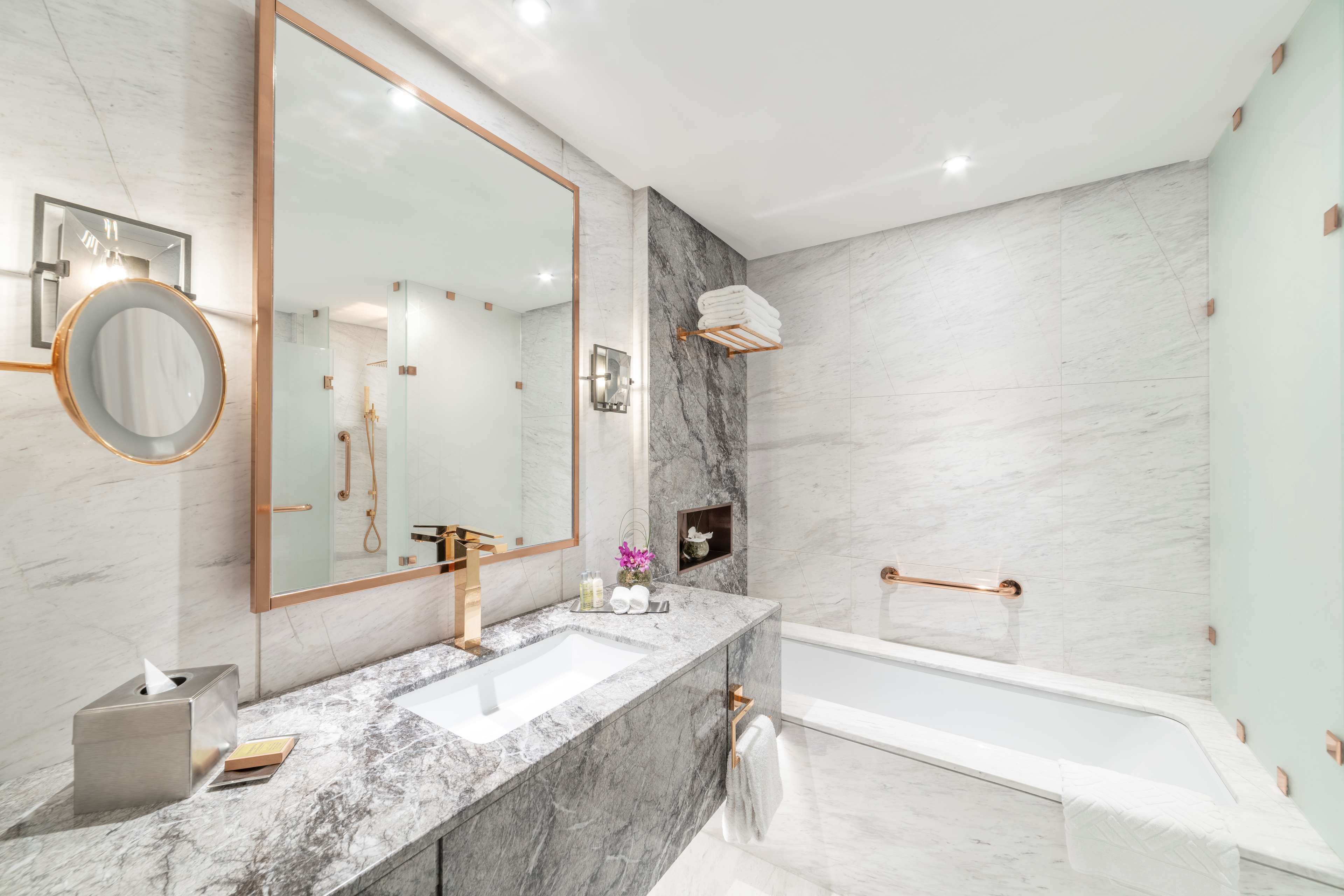Une salle de bain moderne avec un lavabo en marbre, un grand miroir et une baignoire.