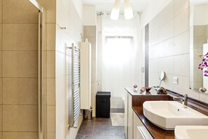 Un bany modern amb un mirall gran, un lavabo i una zona de dutxa.
