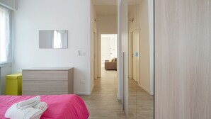 A modern bedroom with a pink bed, a wooden dresser, and a mirror on the wall. - L'appartamento del Portico Mazzini (Bologna)