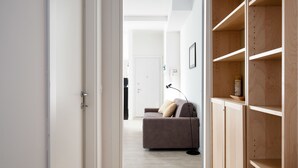 A hallway with a wooden wardrobe, a sofa, and a lamp. - L'appartamento del Portico Mazzini (Bologna)