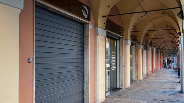 A covered pedestrian walkway with closed shop fronts and a tiled floor. - L'appartamento del Portico Mazzini (Bologna)