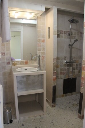 Baño con lavabo, espejo y ducha.