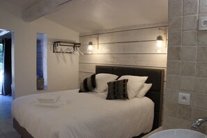 Un dormitorio con una cama grande, cabecera, lámpara de pared y bañera integrada.