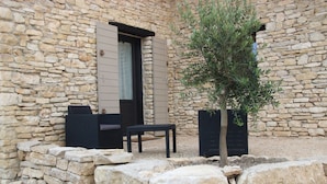 Een stenen gebouw met een klein terras, inclusief een tafel, stoelen, een potplant en een stenen muur.