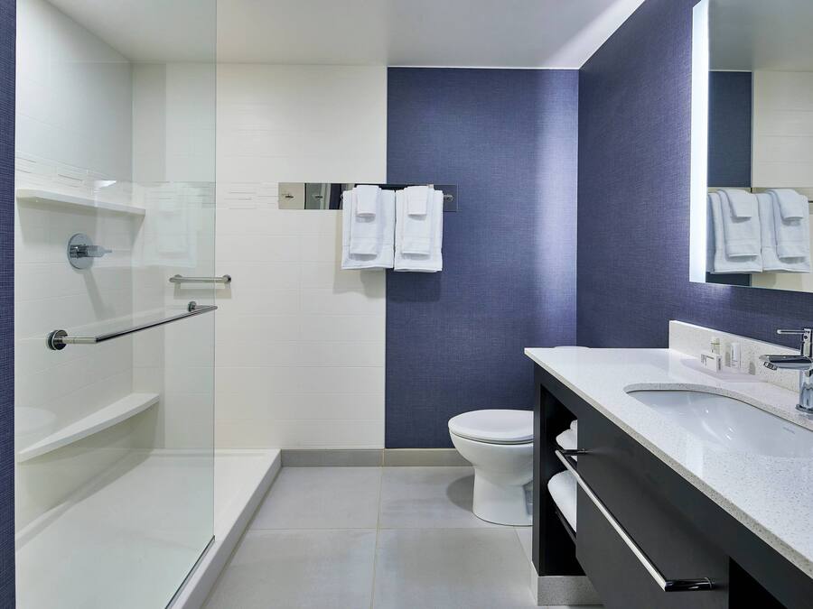 A modern bathroom with a glass shower enclosure, a white toilet, and a vanity with a sink and mirror.