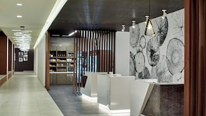 A modern reception area with a counter, a wall with leaf patterns, and a store in the background. - Residence Inn by Marriott Albany Airport (Albany)
