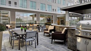 An outdoor patio with a grill, seating area, and a view of the building's exterior. - Residence Inn by Marriott Albany Airport (Albany)