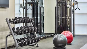 A gym with weightlifting equipment, exercise balls, and a mirror.