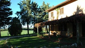 A house with a covered porch, a stone pathway, and a grassy lawn. - Agriturismo Cavallin del Bufalo (Manciano)