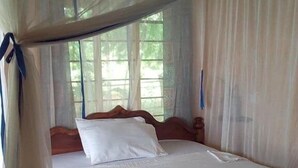 A single bed with a wooden frame and white bedding, covered by a mosquito net. - Chole Foxes lodge (Chole Island)