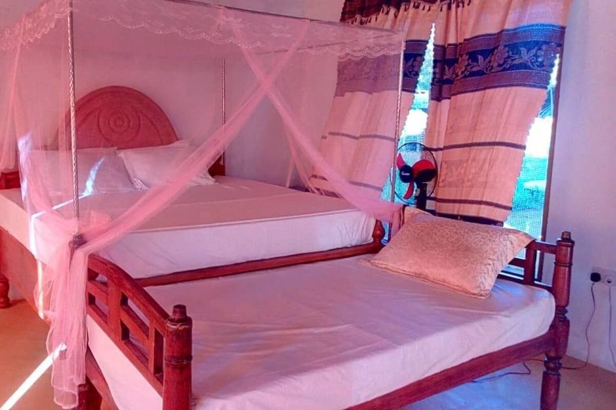 A double bed with a wooden frame, white bedding, and a canopy.