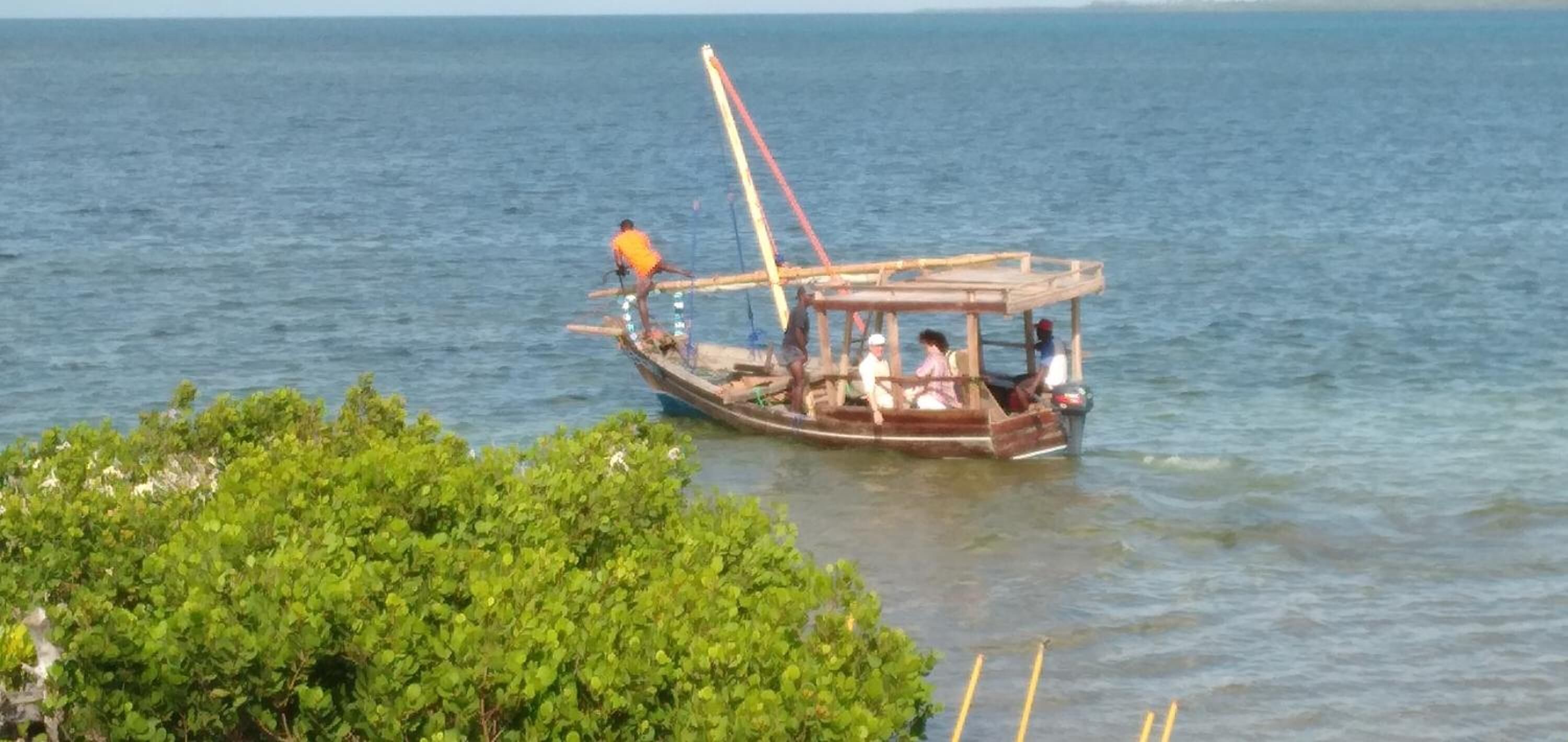 Ein traditionelles Holzboot mit Passagieren auf ruhigem Wasser.
