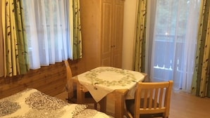 A room with a bed, a table with a tablecloth, a chair, a wardrobe, and large windows with curtains. - Double room 4 - Haus Bleckwand (Gschwendt)