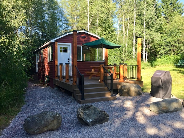 Mökki, jossa on kuisti, piknikpöytä ja grilli.