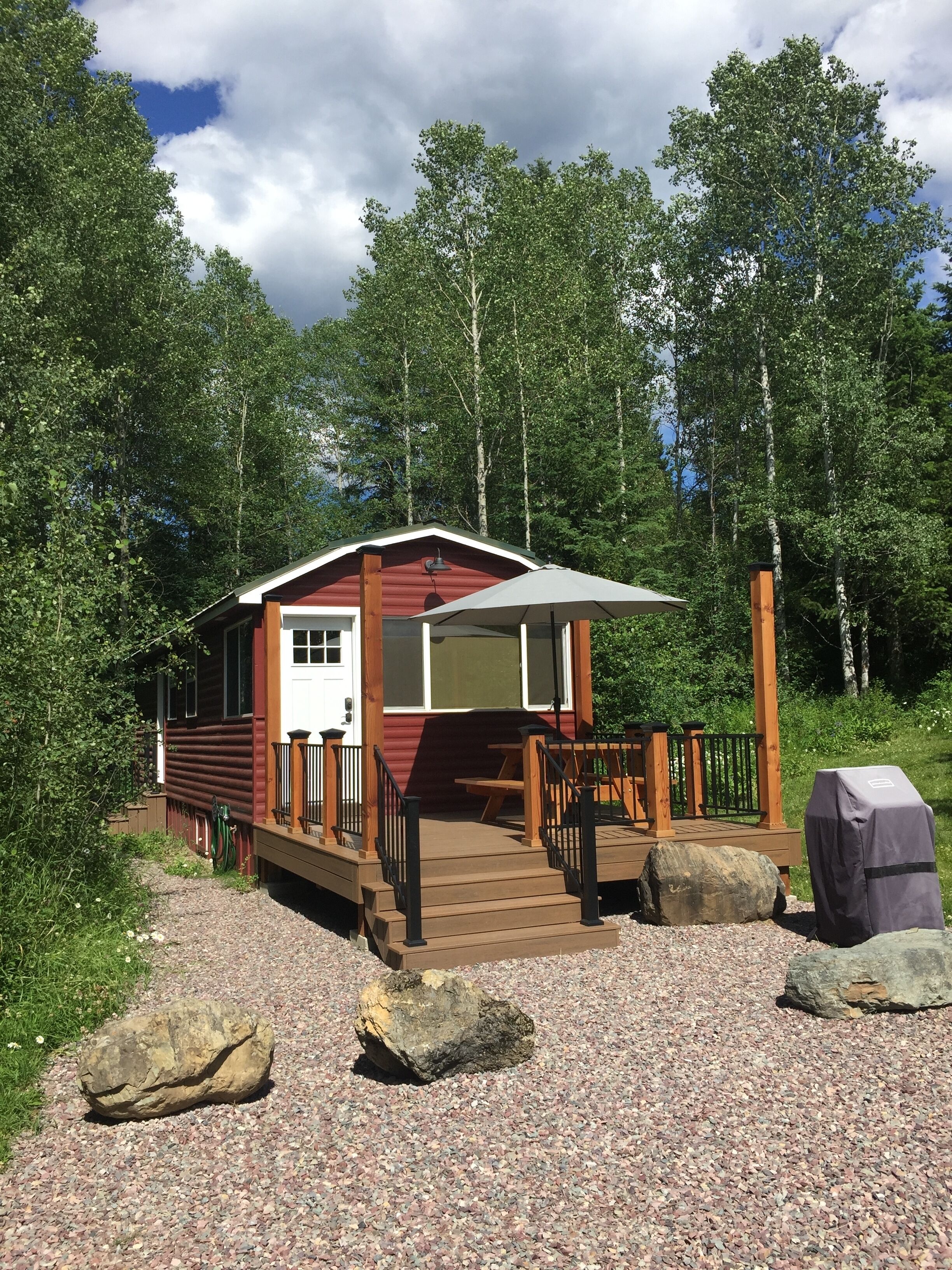 A cabin with a wooden deck, a covered porch, and a picnic table.