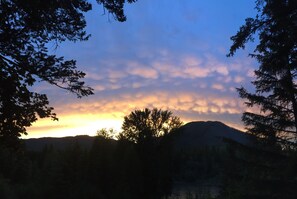 Auringonlaskunäkymä, jossa näkyy vuoria ja puita.