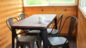 Een houten tafel met vier stoelen, een witte mok en een lepel erop.