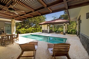 Un área de piscina con sillas de madera y un pabellón.