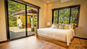 Un dormitorio con un amplio ventanal corredera que da a un patio exterior.