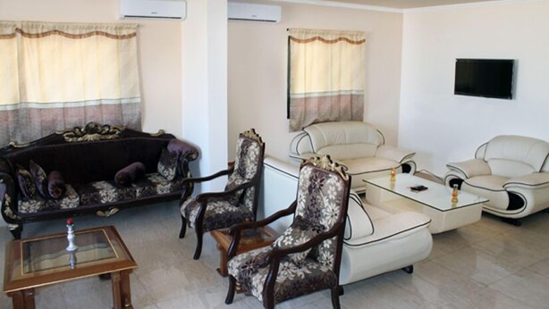 A living room with a sofa, armchairs, a coffee table, and a TV mounted on the wall.