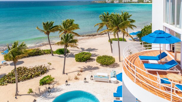 A resort with a pool, lounge chairs, and a view of the ocean. - Altamer Resort (West End Village)