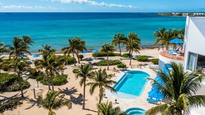 A resort with a pool, palm trees, and a view of the ocean. - Altamer Resort (West End Village)