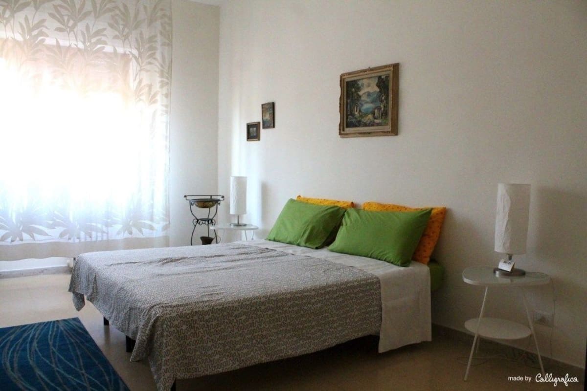 A bedroom with a bed, a bedside table, a lamp, and a painting on the wall.