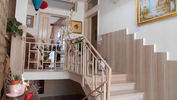 A staircase with a wooden railing, a potted plant, and a framed painting on the wall.