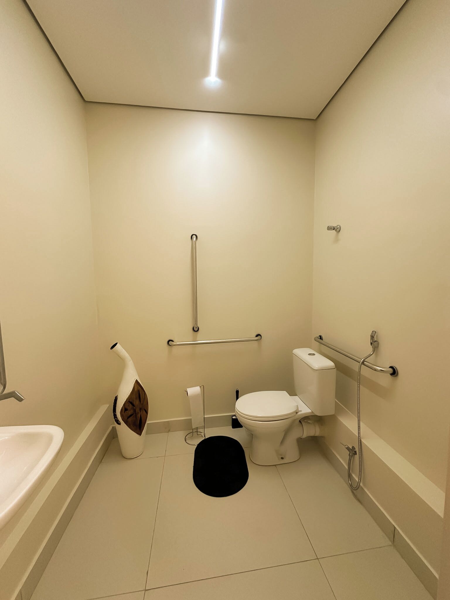 A small, well-lit bathroom with a toilet, sink, and grab bars.