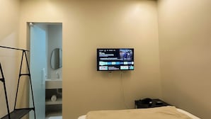 Une chambre à coucher moderne, avec un lit, un téléviseur fixé au mur, une armoire et un miroir.