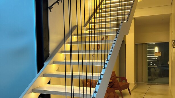 Un escalier moderne au design minimaliste, doté d’une main courante blanche et de balustres noires.