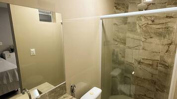A modern bathroom with a glass-enclosed shower, a marble sink, and a toilet.