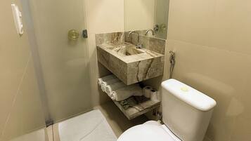 A modern bathroom with a glass shower enclosure, a marble sink, and a toilet.