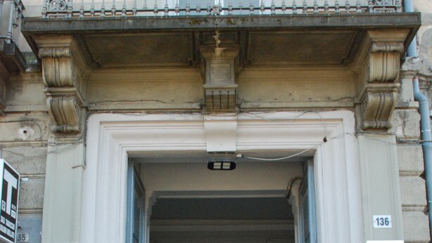 A building entrance with a large doorway, a balcony with decorative railings, and a number sign '136' on the wall. - Garibaldi 136 (Naples)