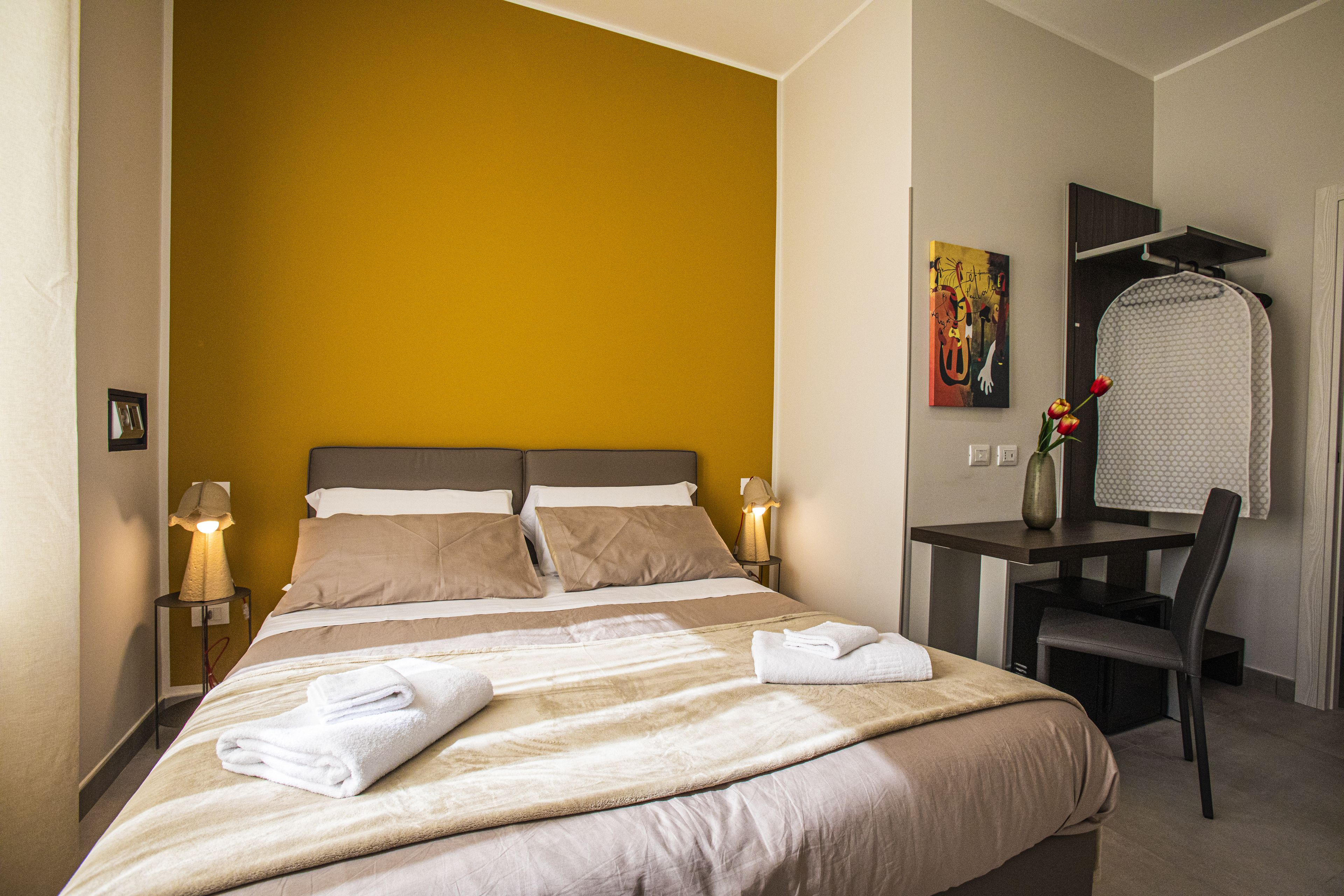 A hotel room with a bed, bedside tables, a desk, and a chair.