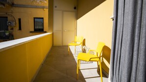 A narrow balcony with yellow walls, a white railing, and two yellow chairs. - Garibaldi 136 (Naples)