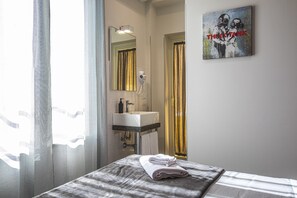 A hotel room with a bed, a bathroom with a sink, and a painting on the wall. - Garibaldi 136 (Naples)