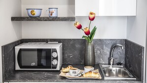 A kitchen with a microwave, sink, and a vase with tulips. - Garibaldi 136 (Naples)