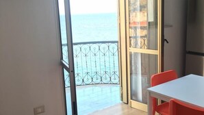 A room with a balcony, a white table, and red chairs. - CasaMIA a Marina di Camerota (Camerota)