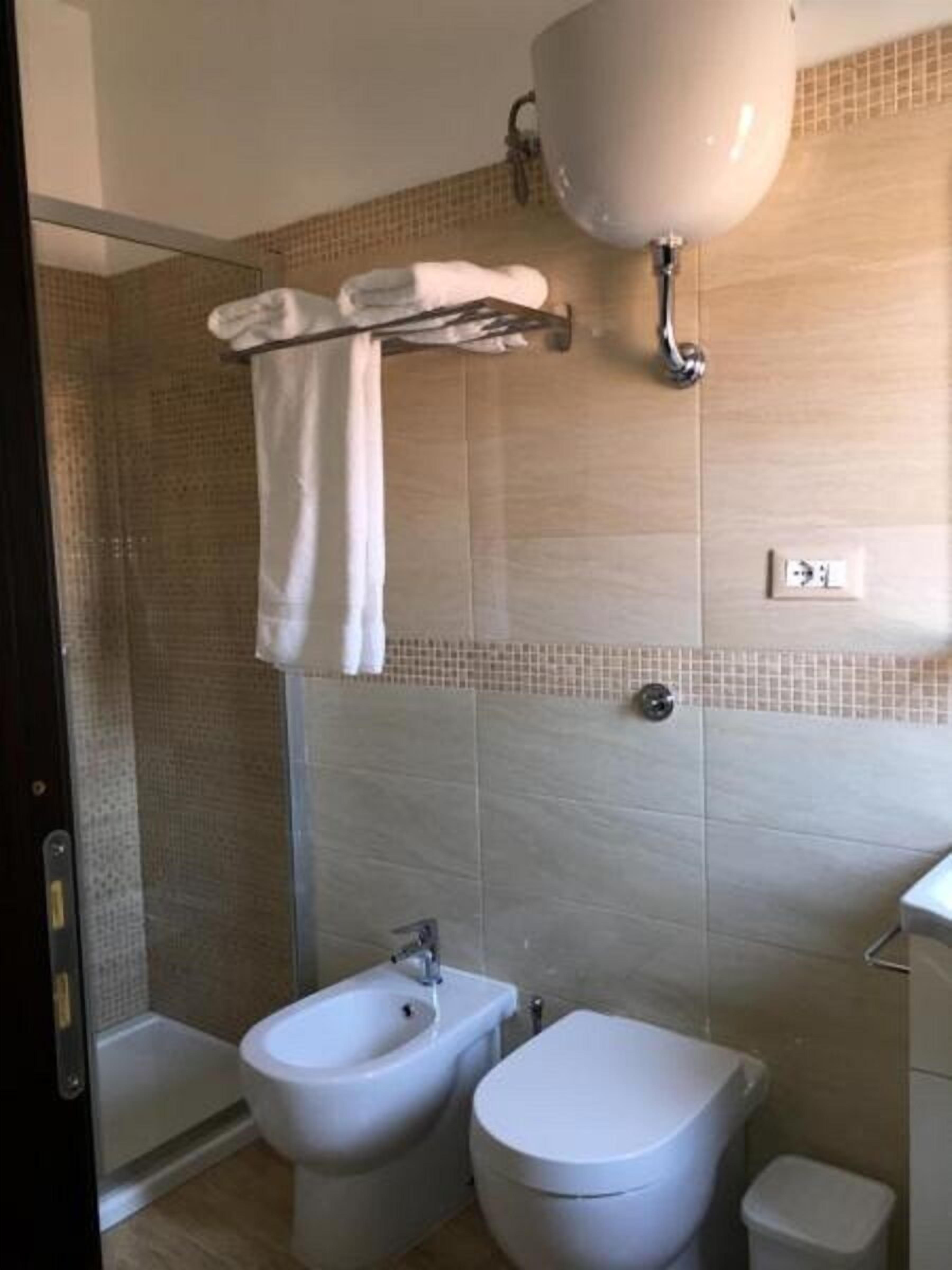 A bathroom with a shower, bidet, toilet, and a towel rack.