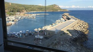 A coastal marina with boats docked, a rocky breakwater, and a view of the sea and hills in the distance. - CasaMIA a Marina di Camerota (Camerota)
