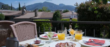 A breakfast table with plates of food, a pitcher, and glasses of orange juice, overlooking a scenic mountain view.