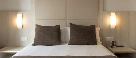Una habitación de hotel con una cama grande, dos mesitas de noche y lámparas de pared.